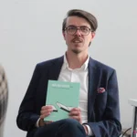 Pan Kamil Kowalski – Dyrektor Integracja LAB, trzyma w rękach publikację swojego autorstwa pt. “Włącznik 2.0 projektowanie bez barier”